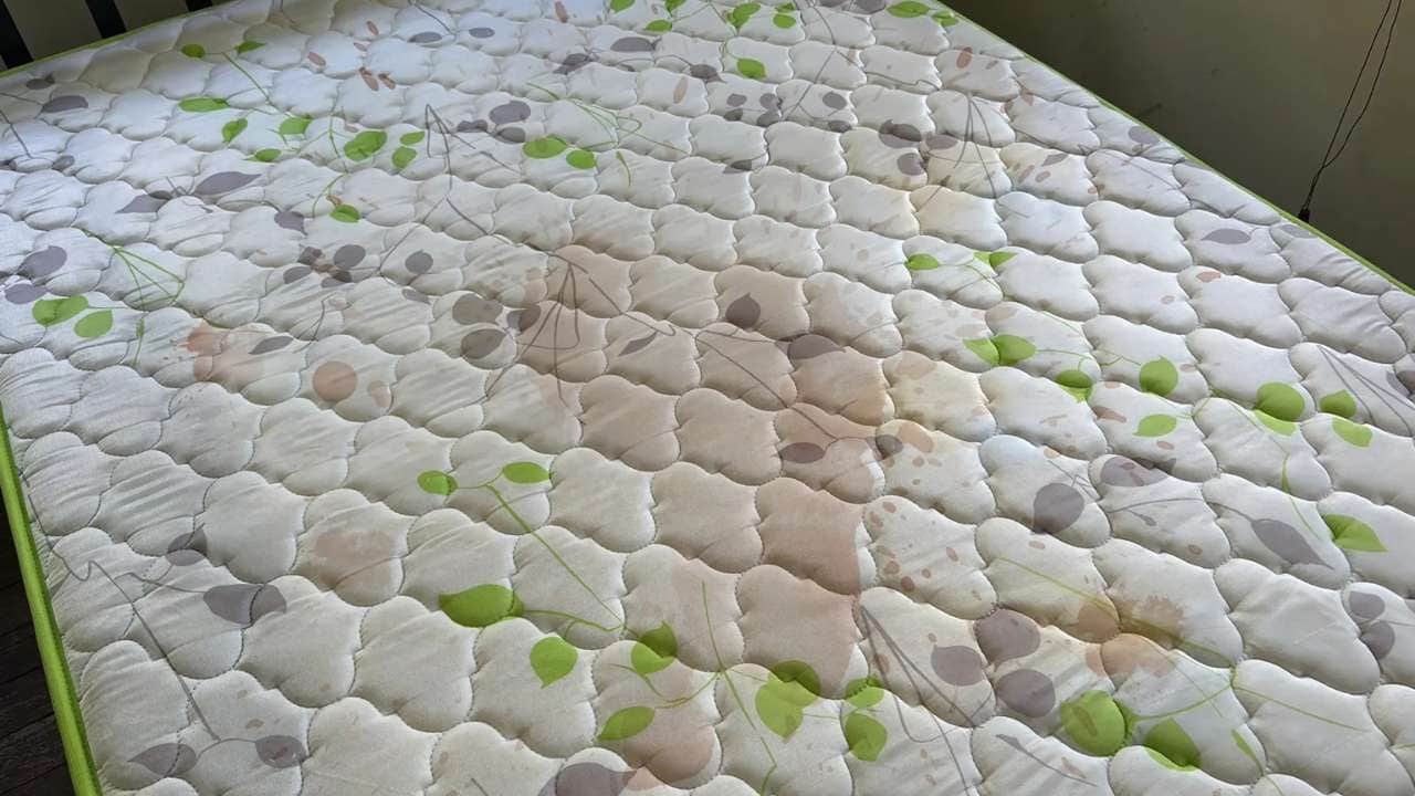 Mattress with visible stains before professional mattress cleaning